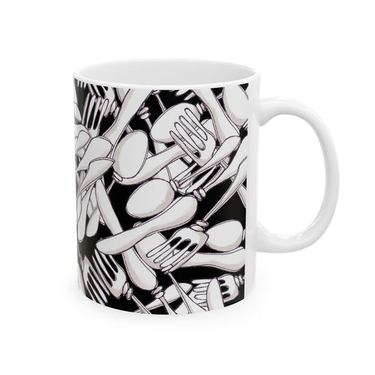 White mug with a black pattern of overlapping forks and spoons, creating a dense, abstract design.