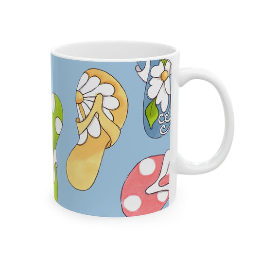 White mug with colorful flip-flops and flowers on a light blue background.
