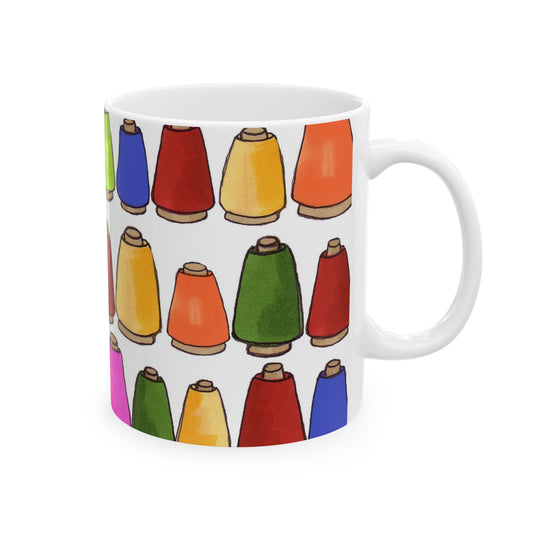 White mug with a pattern of colorful thread spools in red, blue, green, orange, and yellow.