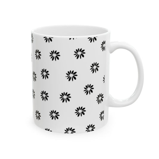 White mug with black daisy pattern, featuring a glossy finish and a sturdy handle.