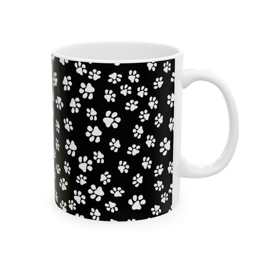 White mug with black background covered in white paw prints.