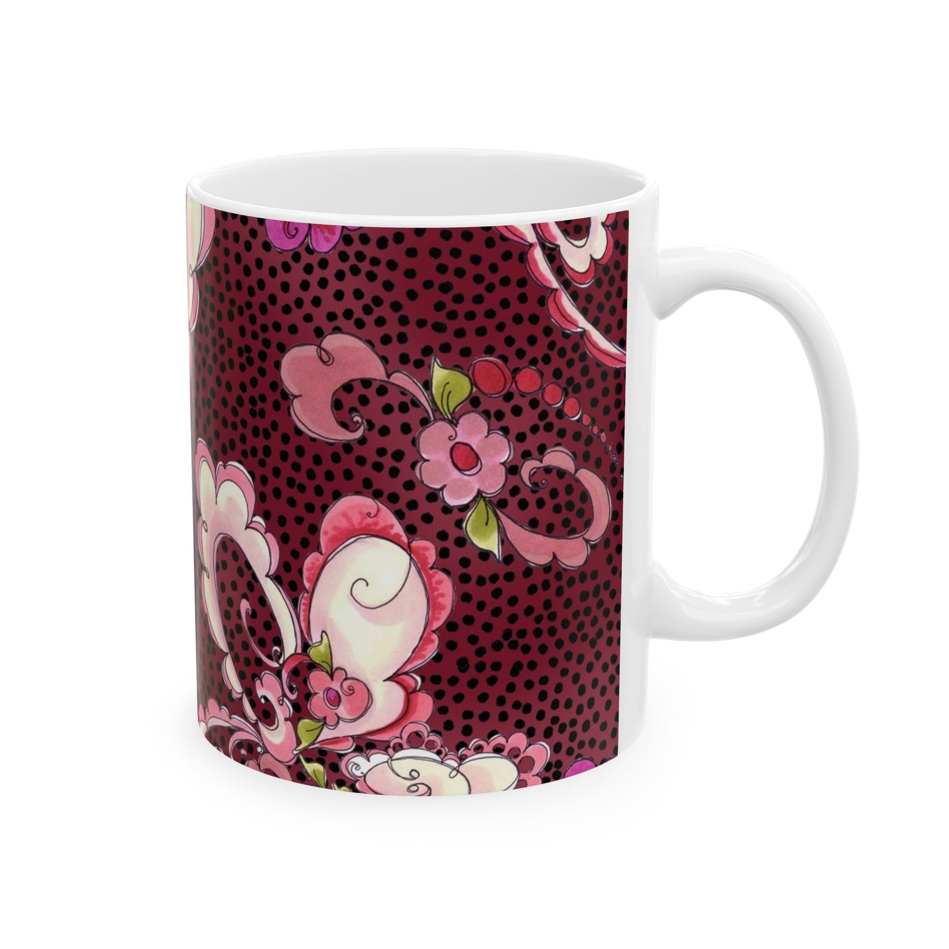 White mug with pink floral patterns and green leaves on a dark red, dotted background.