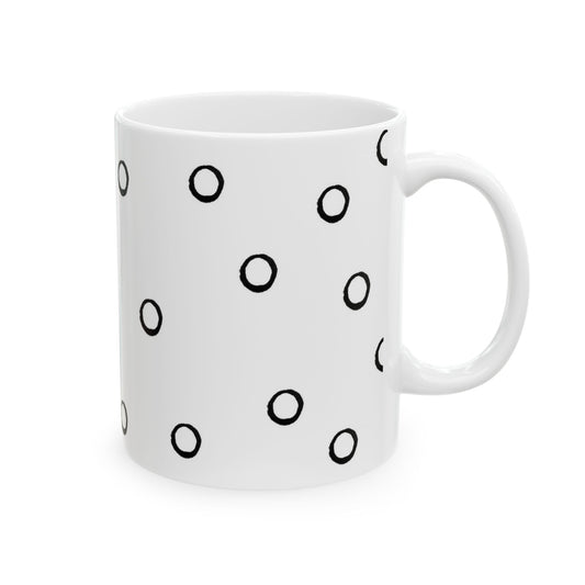 White mug with black circular ring pattern scattered across the surface.