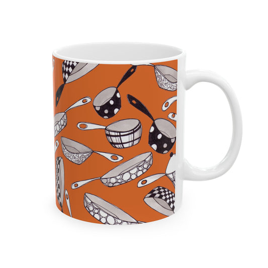 White mug with orange background, featuring black and white patterned kitchenware illustrations.