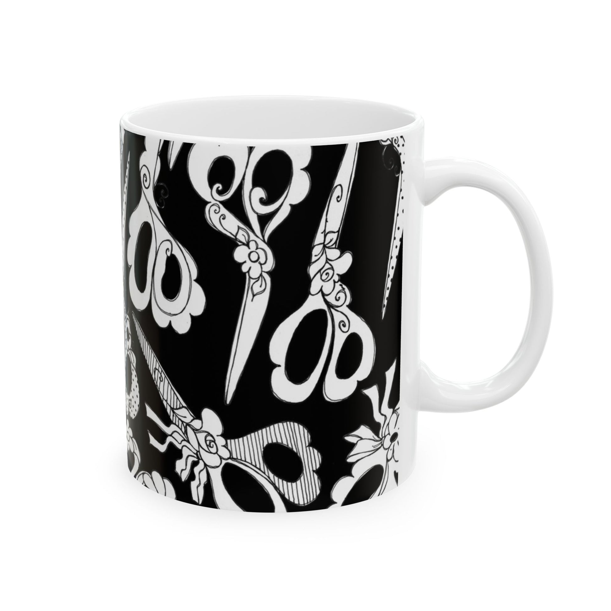 White mug with black background, featuring intricate white scissor patterns and floral designs.