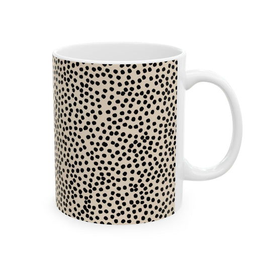 White mug with black irregular polka dots on a beige background.