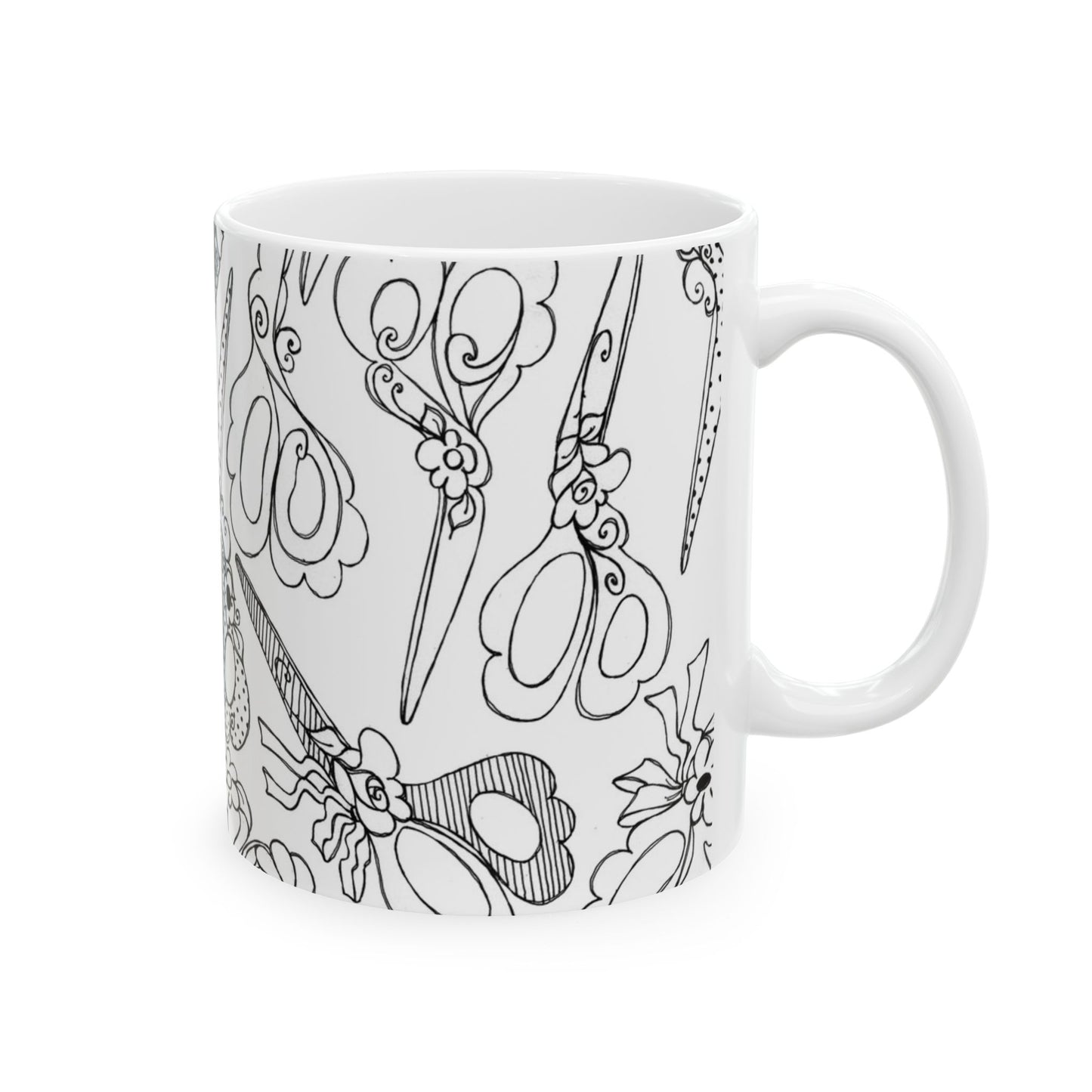 White mug with intricate black scissor designs, featuring floral and swirl patterns.
